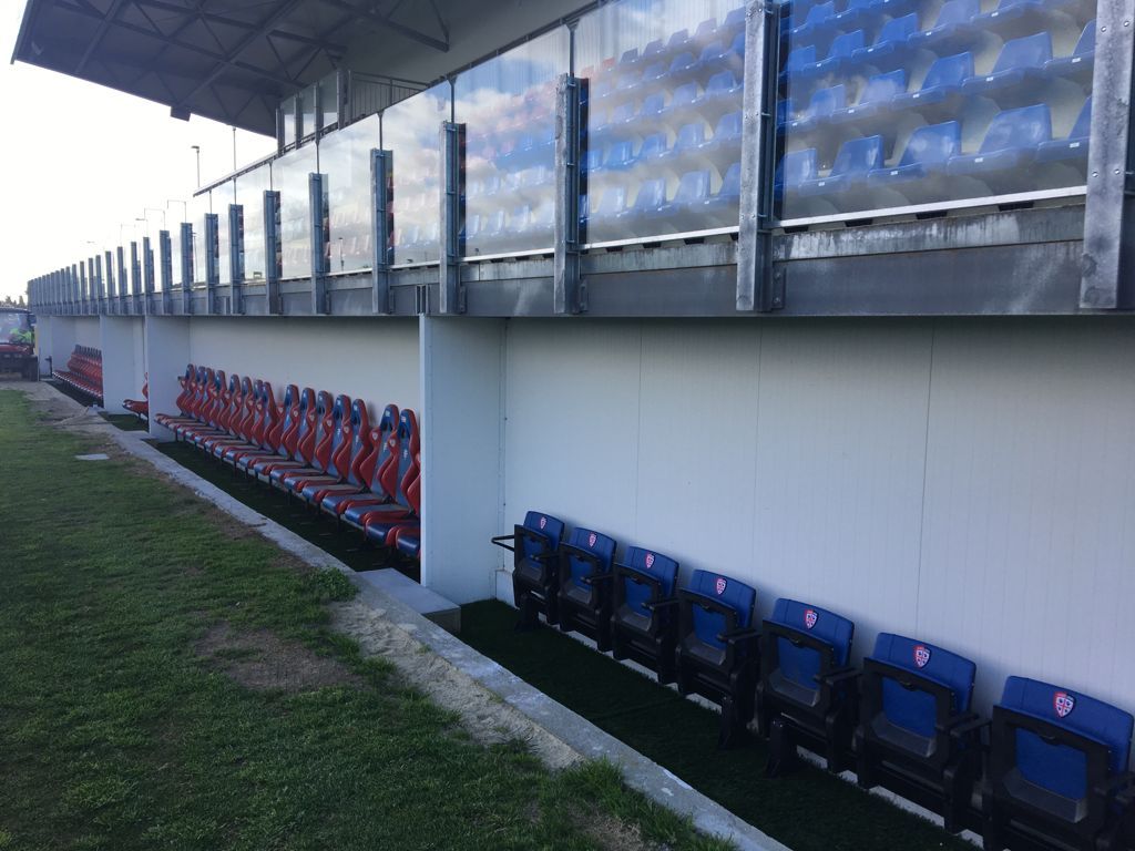 Una fila di sedili blu e rossi in uno stadio.