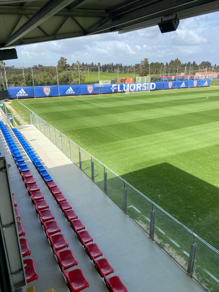 Una vista di un campo da calcio da uno stadio con sedili rossi e blu.