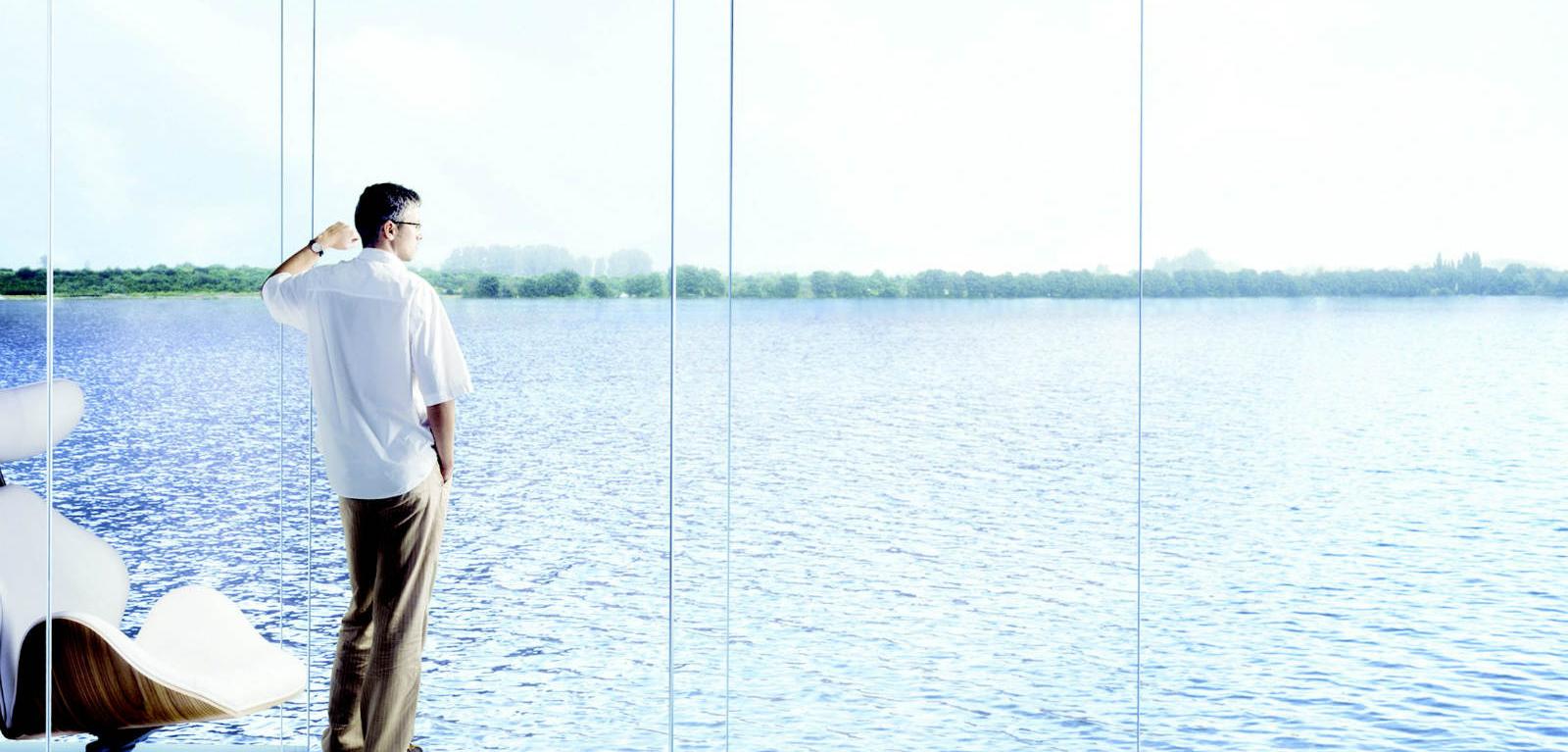 Un uomo è in piedi davanti a un grande specchio d'acqua.