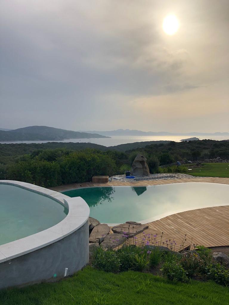 Una grande piscina con vista sul lago e sulle montagne sullo sfondo.
