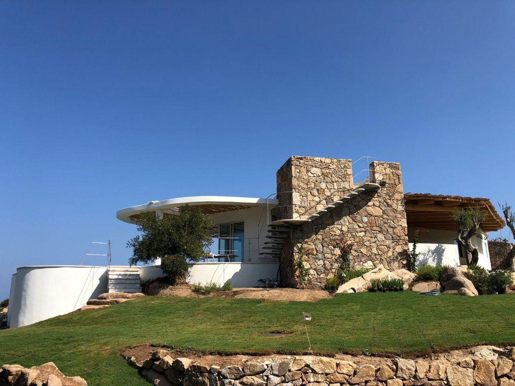 Una casa con le scale che vi conducono è situata in cima a una collina erbosa.