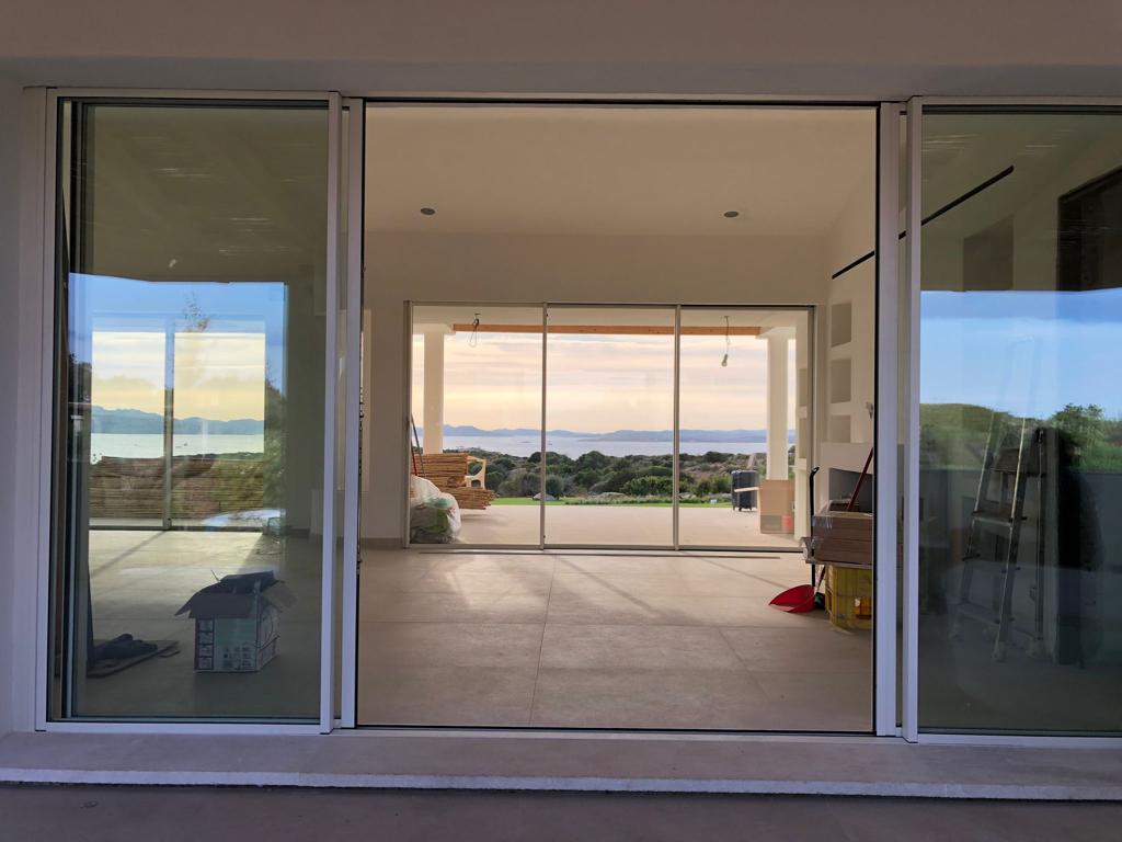 Una porta scorrevole in vetro si apre su una grande stanza con vista sull'oceano.