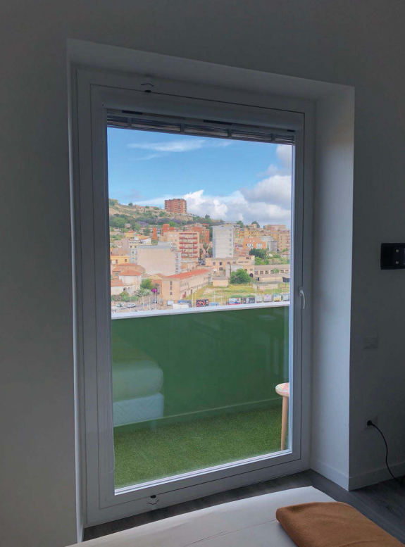 Una camera da letto con una grande finestra con vista su una città.