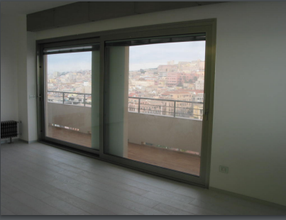 Una stanza vuota con porte scorrevoli in vetro che conducono ad un balcone