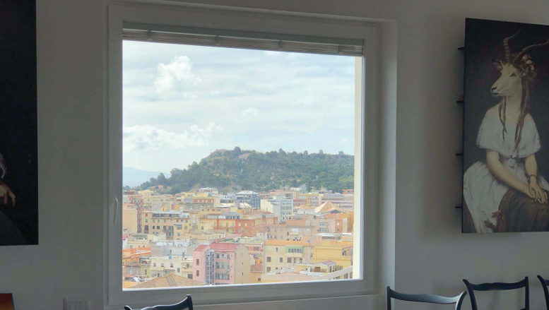 Una stanza con una grande finestra e un quadro alla parete.
