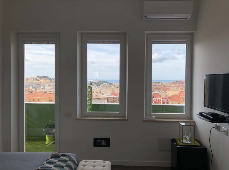 Una camera da letto con tre finestre e tv a schermo piatto.