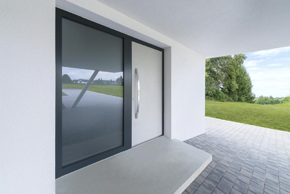 Su un muro bianco c'è una porta bianca con una cornice nera.