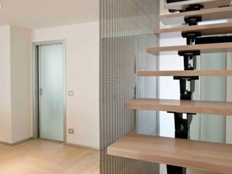 Una stanza con una scala e una porta a vetri