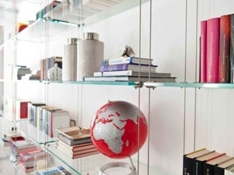 Una mensola di vetro con libri e un globo rosso sopra