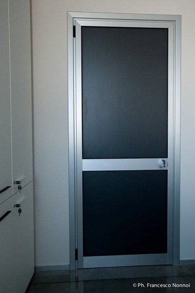 In una stanza è aperta una porta nera con cornice argentata