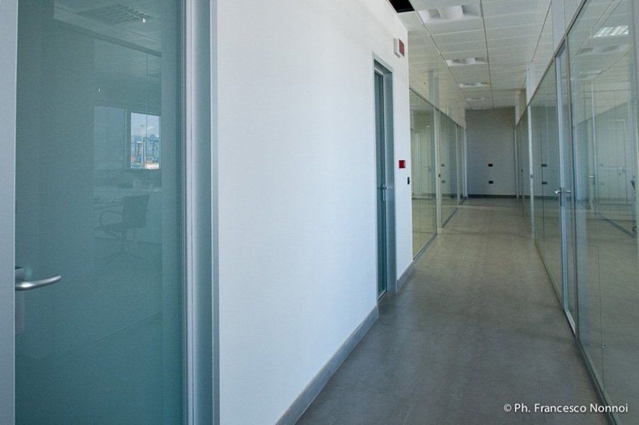 Un lungo corridoio in un edificio per uffici con porte in vetro