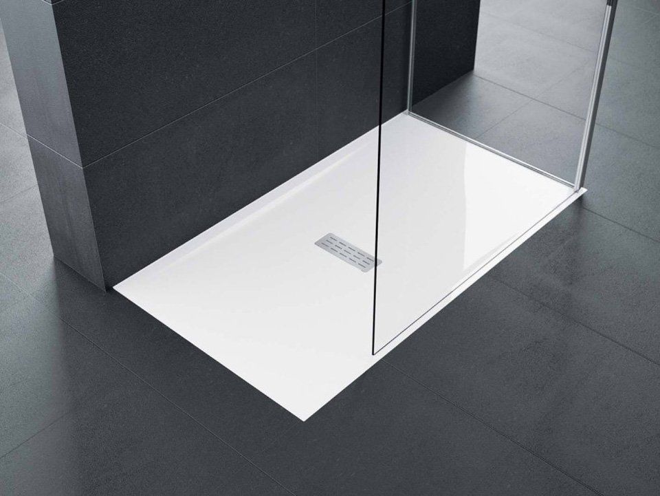 Un piatto doccia bianco in un bagno con porta in vetro