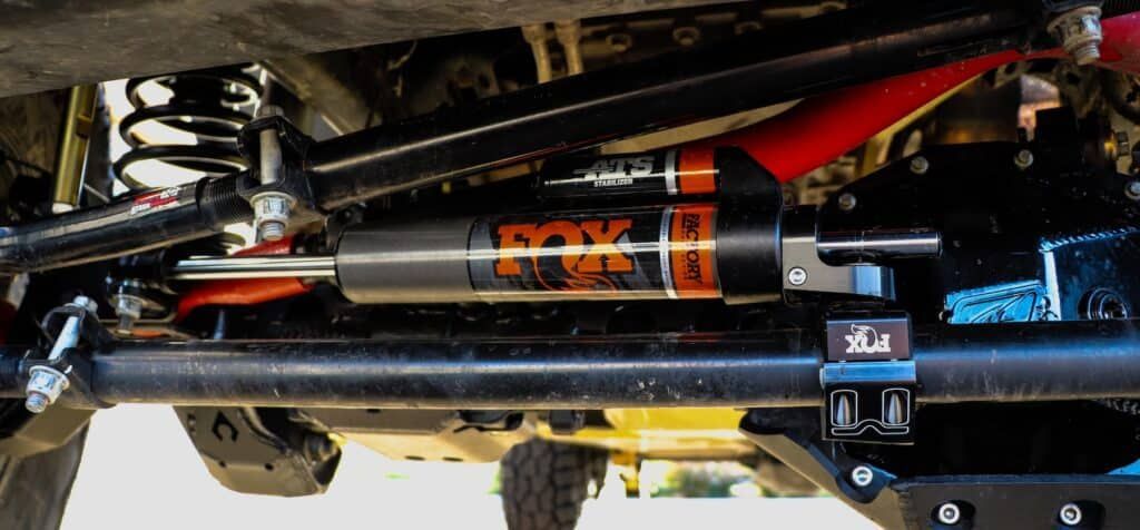 Close-up of a truck’s undercarriage showing a Fox shock absorber and suspension components.