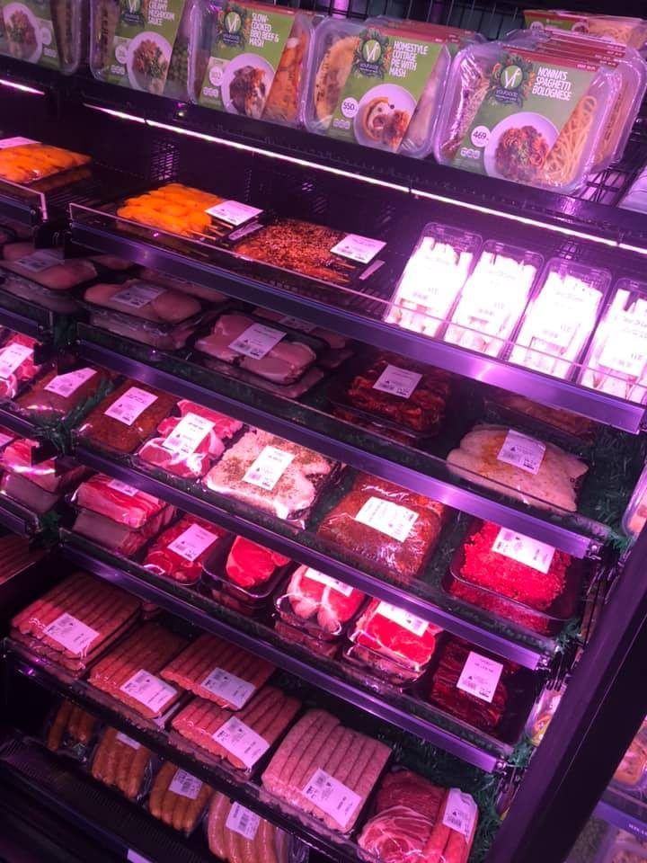 A variety of meats and vegetables are displayed on shelves in a grocery store. — Smith Street Supermarket In Darwin City, NT