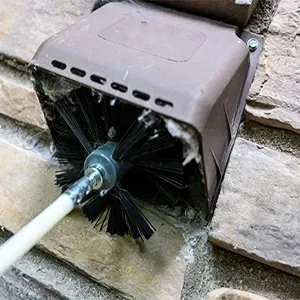 Black brush seal around a white cable passing through a brown wall vent box
