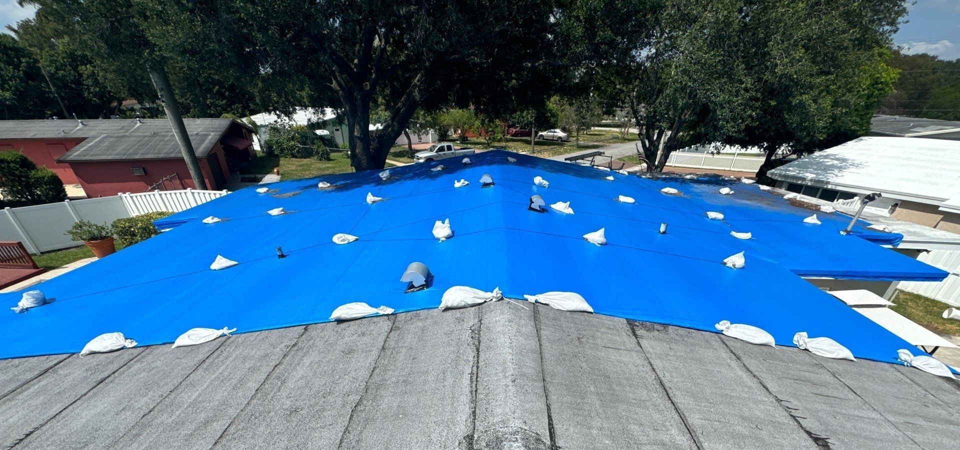 Home's roof in Plantation Fl partially covered with blue tarp for emergency roofing