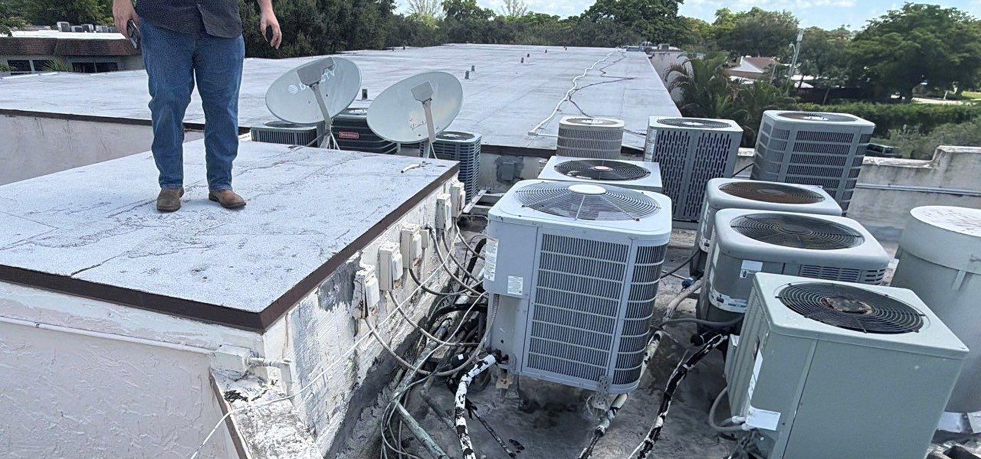 A man next to roof AC units for roof inspection on commercial building in Plantation FL