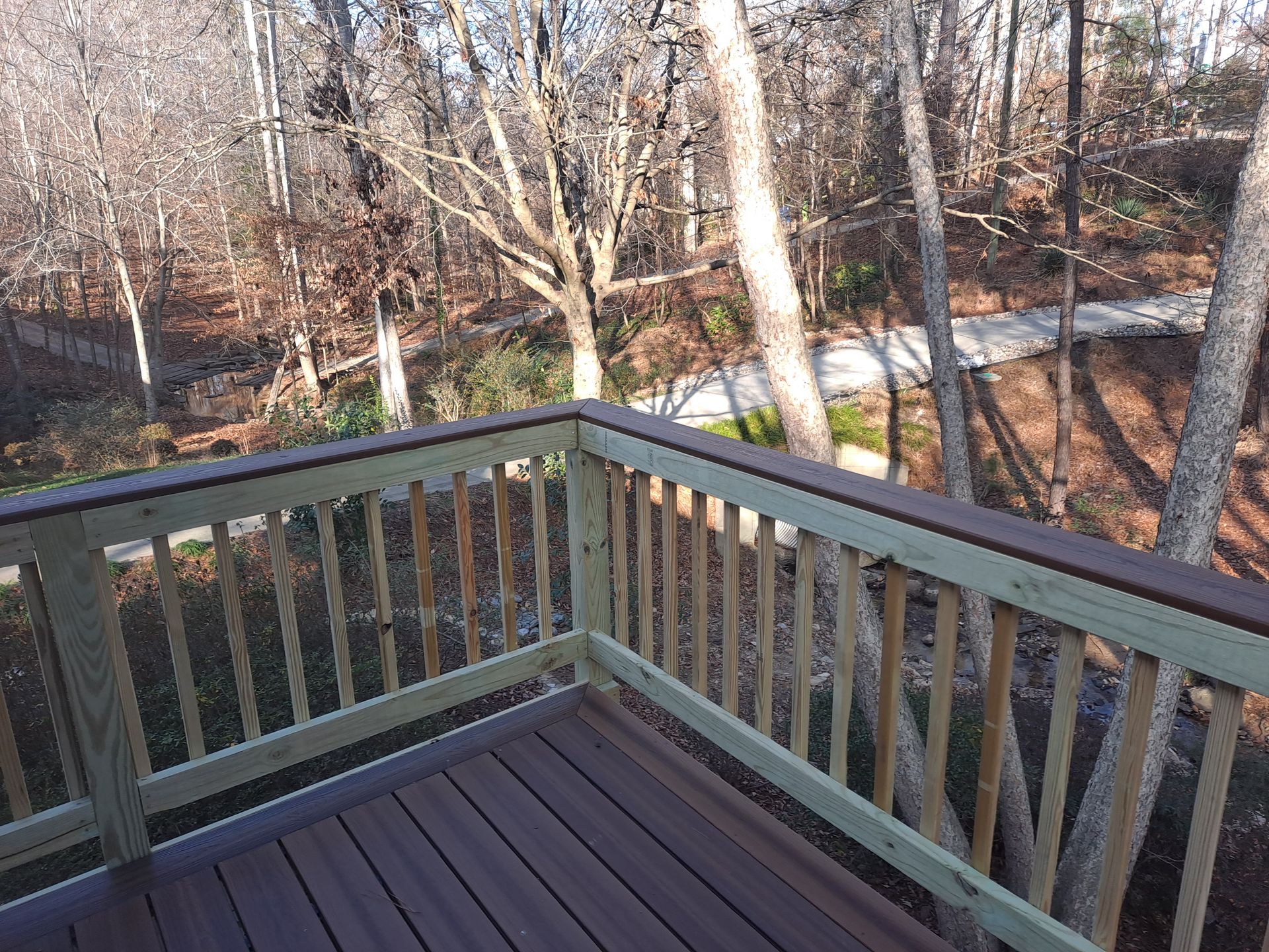 A wooden deck with a wooden railing overlooking a forest.