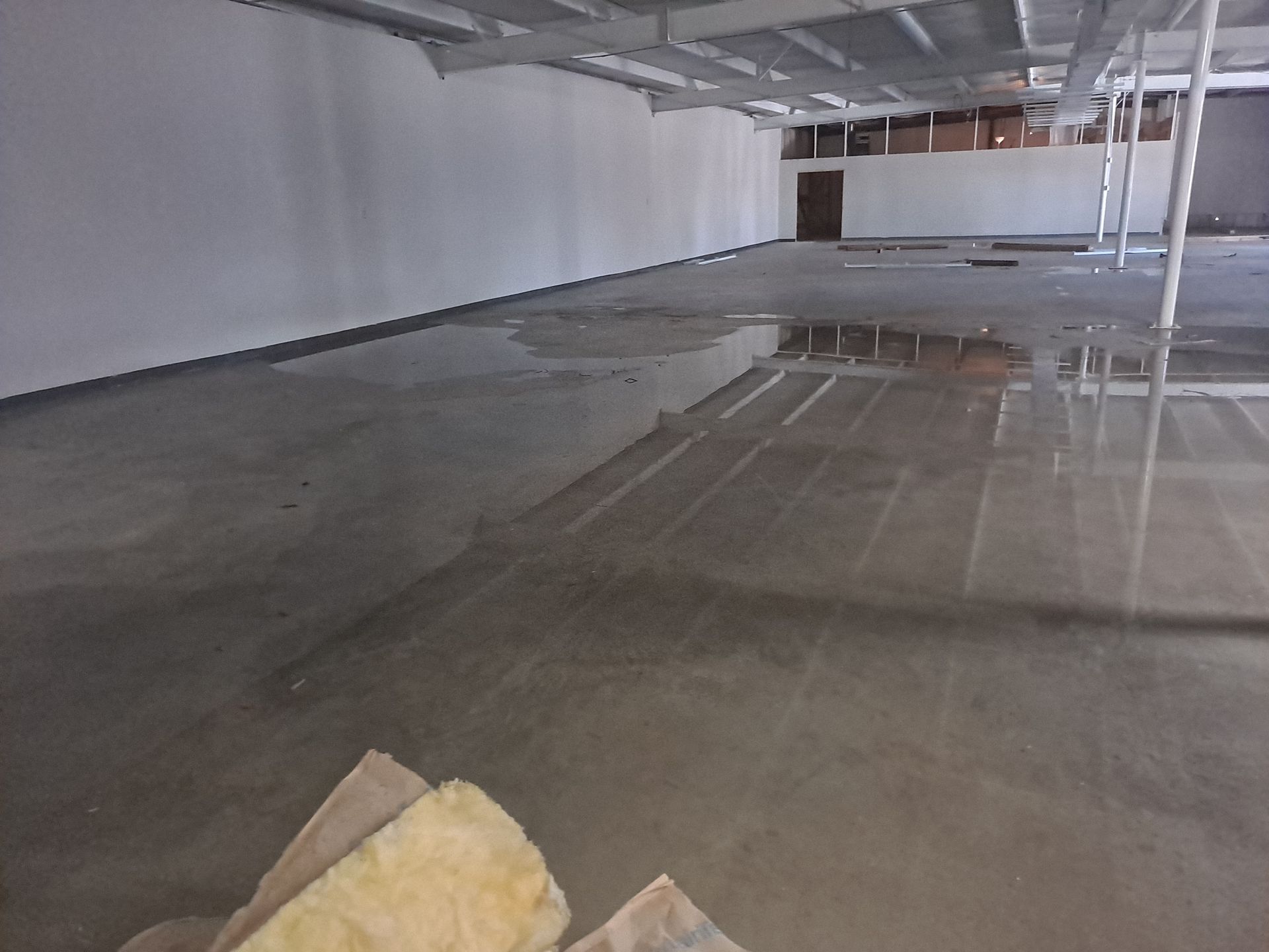A large empty room with a puddle of water on the floor
