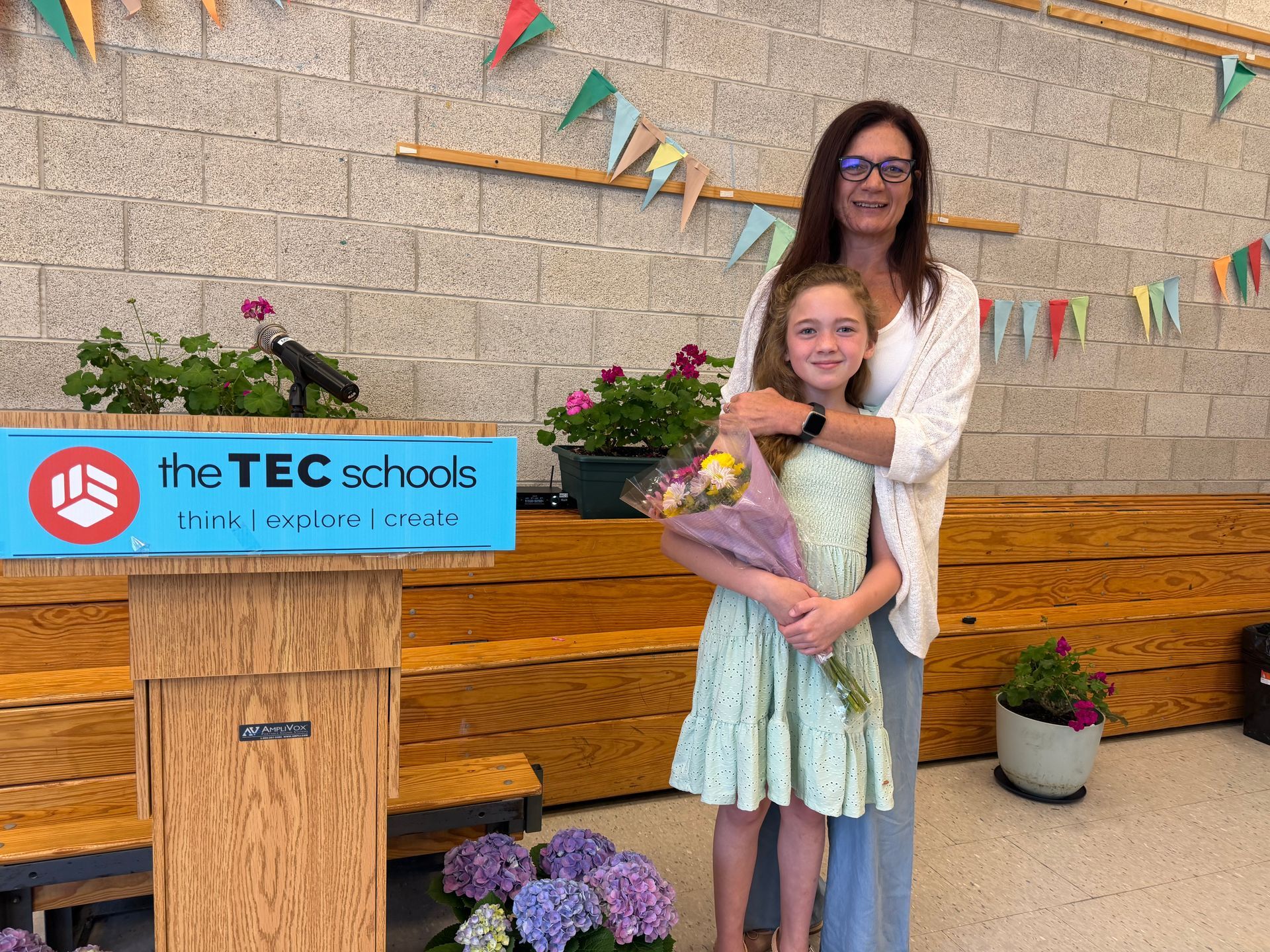 Two people smiling beside a TEC podium with flowers and bunting, in a decorated venue