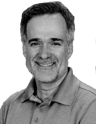 Smiling man in a gray polo shirt against a plain light background