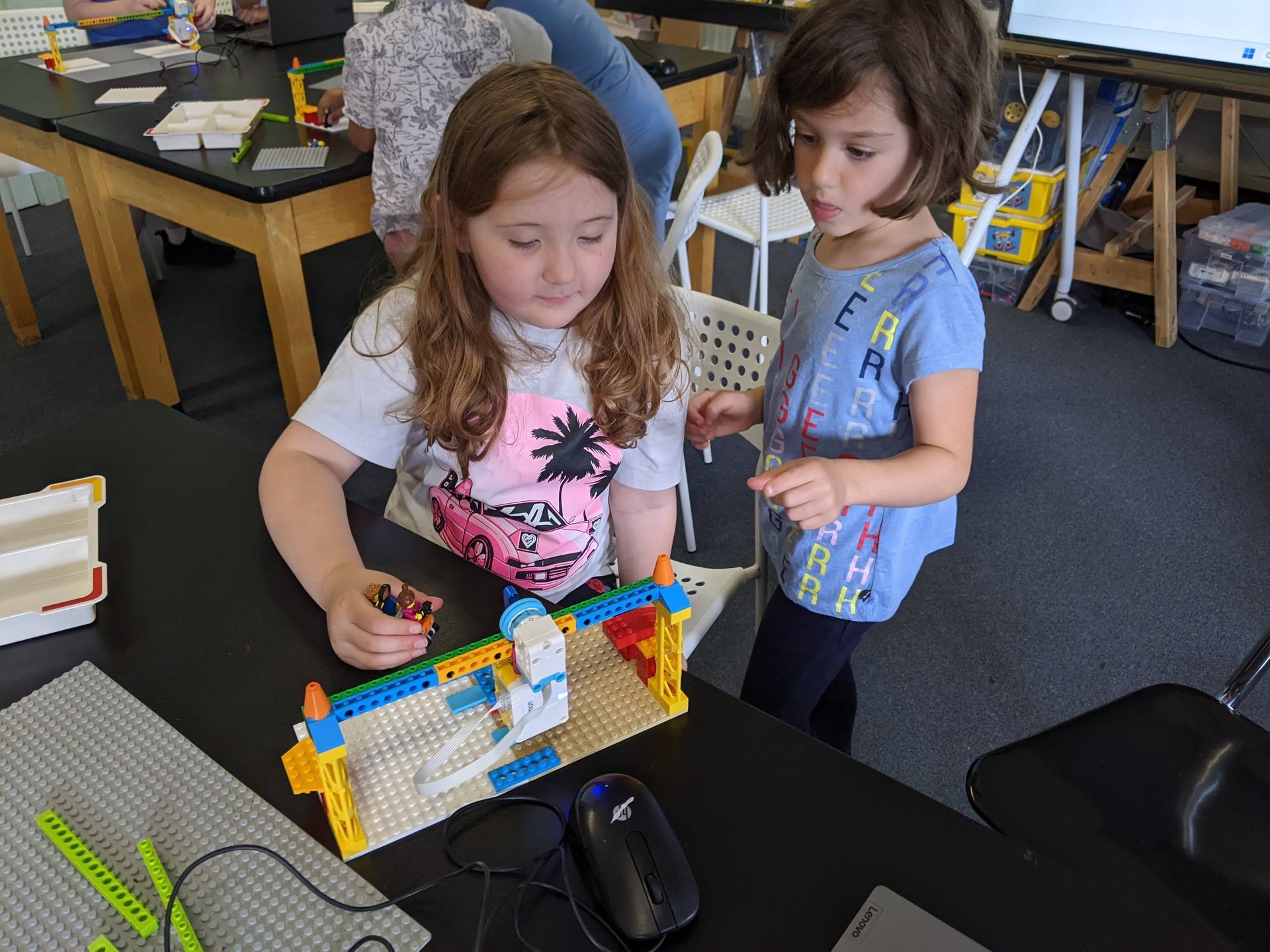 Two children playing with a colorful building set at a table in a classroom