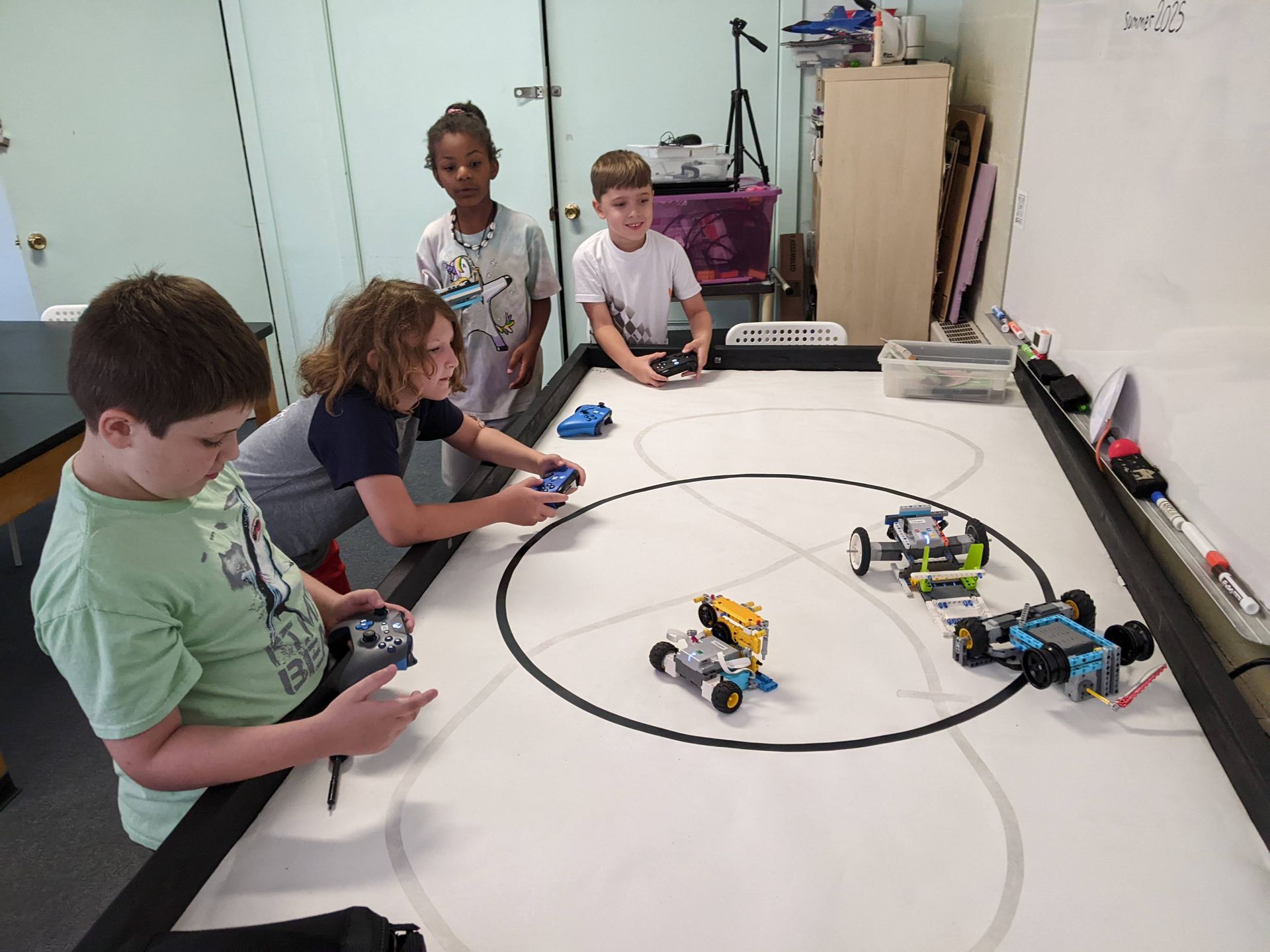 Children in a classroom using robots on a large table with a circular track