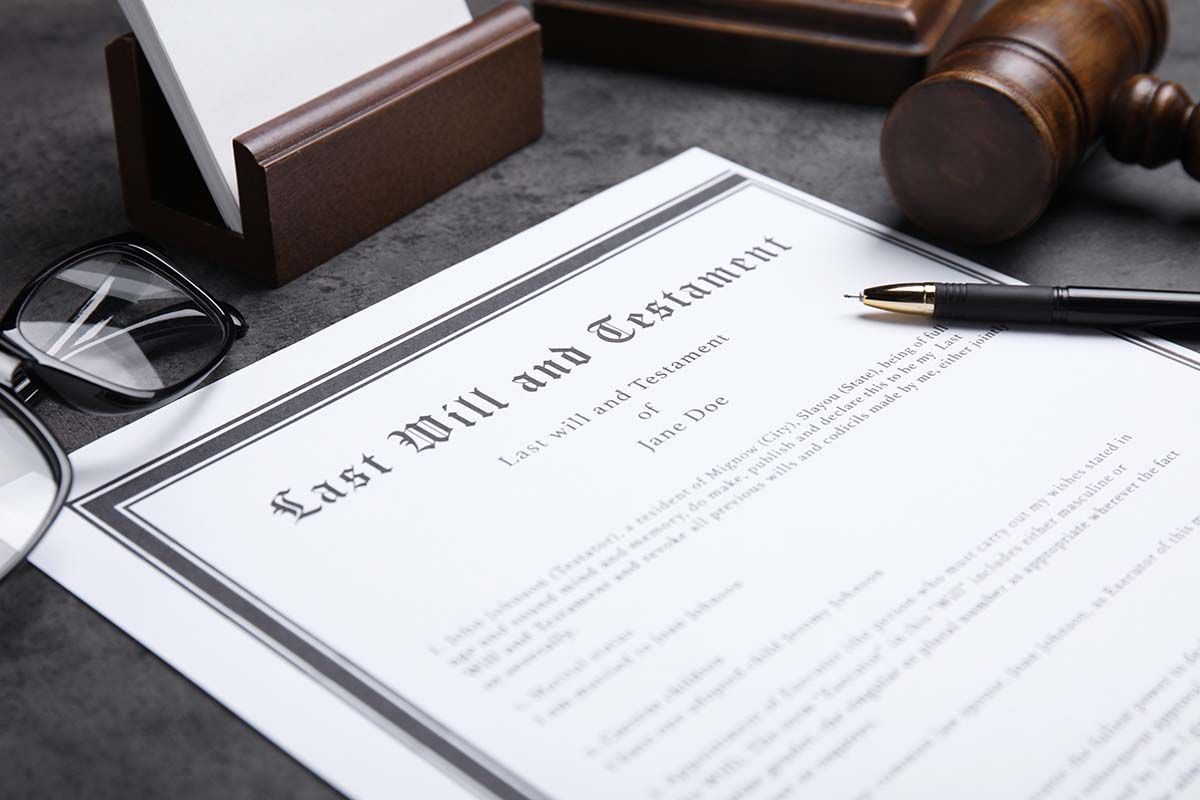 Last will and testament document with gavel, pen, and eyeglasses on a desk
