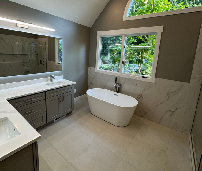 Modern black-and-white bathroom with a freestanding tub, marble walls, and a window.