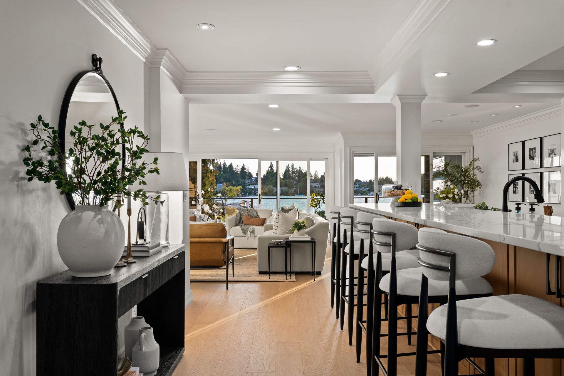 Bright open kitchen with island seating, white cabinetry, and a sunlit living area beyond.