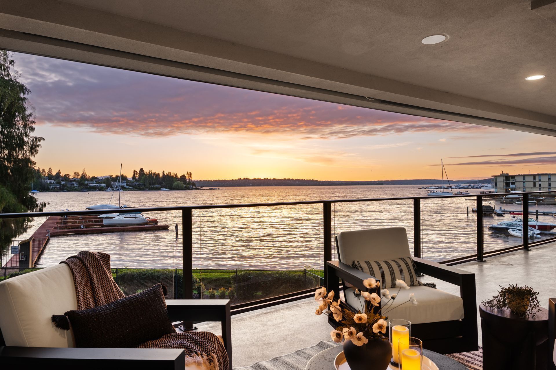 Bright open kitchen and living area with white island, bar stools, fireplace, and large windows.
