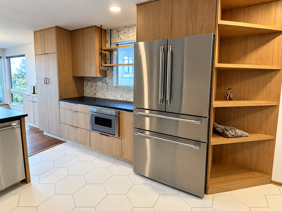 Modern kitchen with wood cabinets, stainless steel refrigerator, oven, and white hexagon tile floor