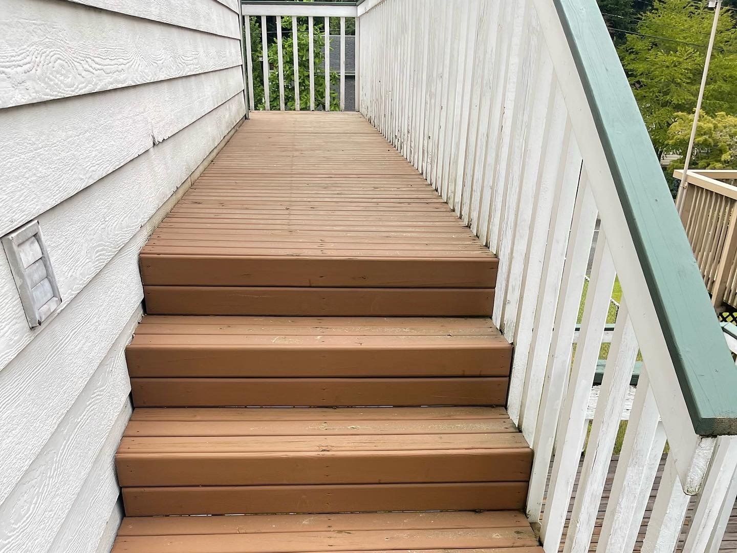 Wooden staircase with white railing, leading to a small deck.