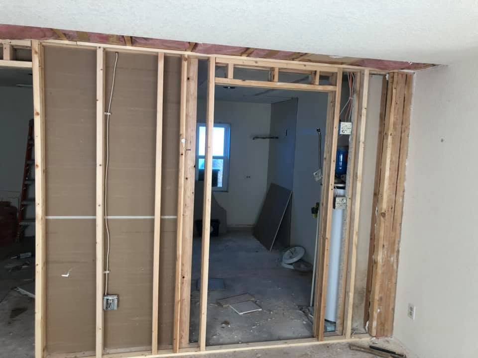 Exposed wooden framing around a large doorway during interior renovation in a white room