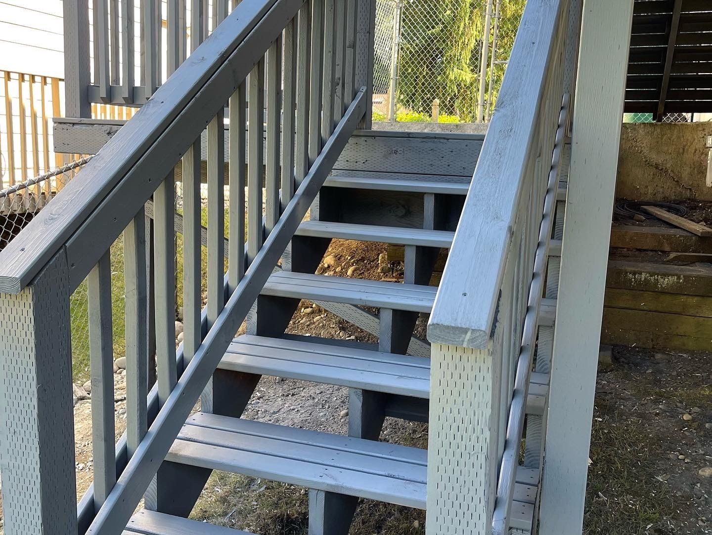 Gray wooden outdoor staircase leading up, with railing on each side.