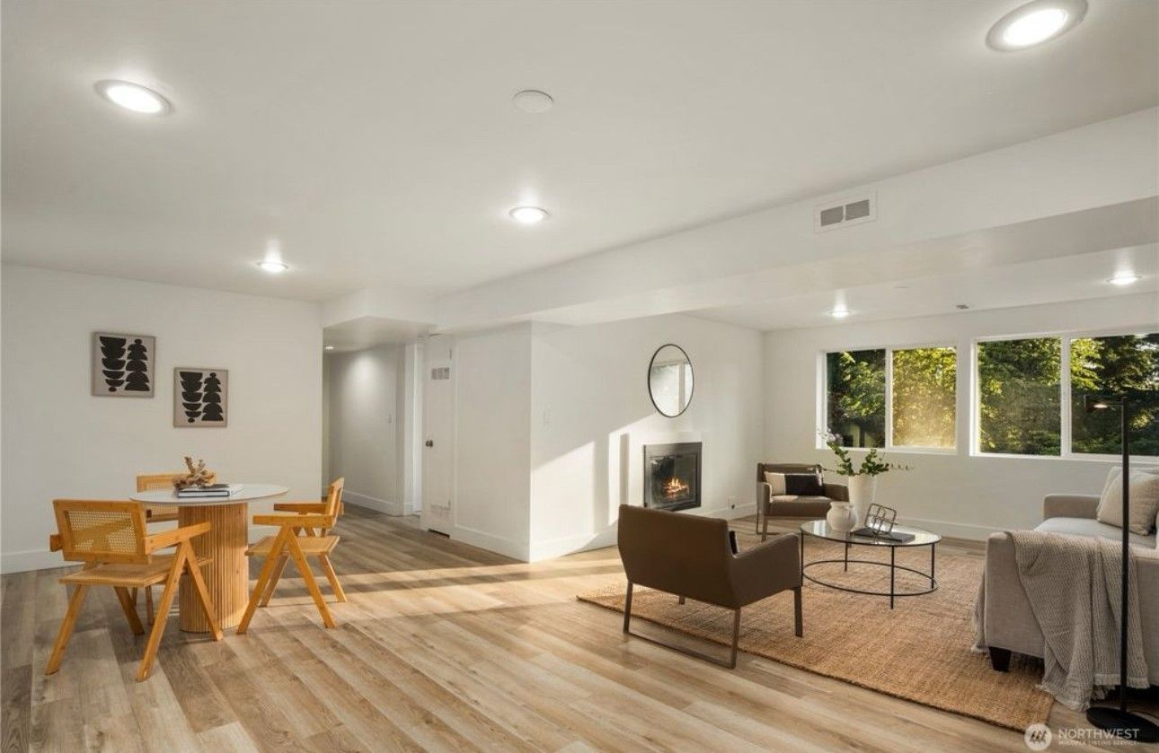 Spacious, bright living area with dining table, fireplace, and large windows.