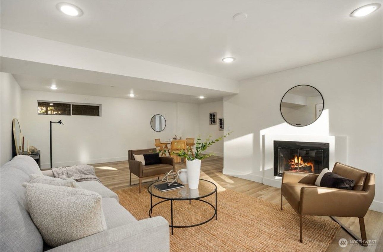 Bright living room with fireplace, seating, round coffee table, and dining table in the background.