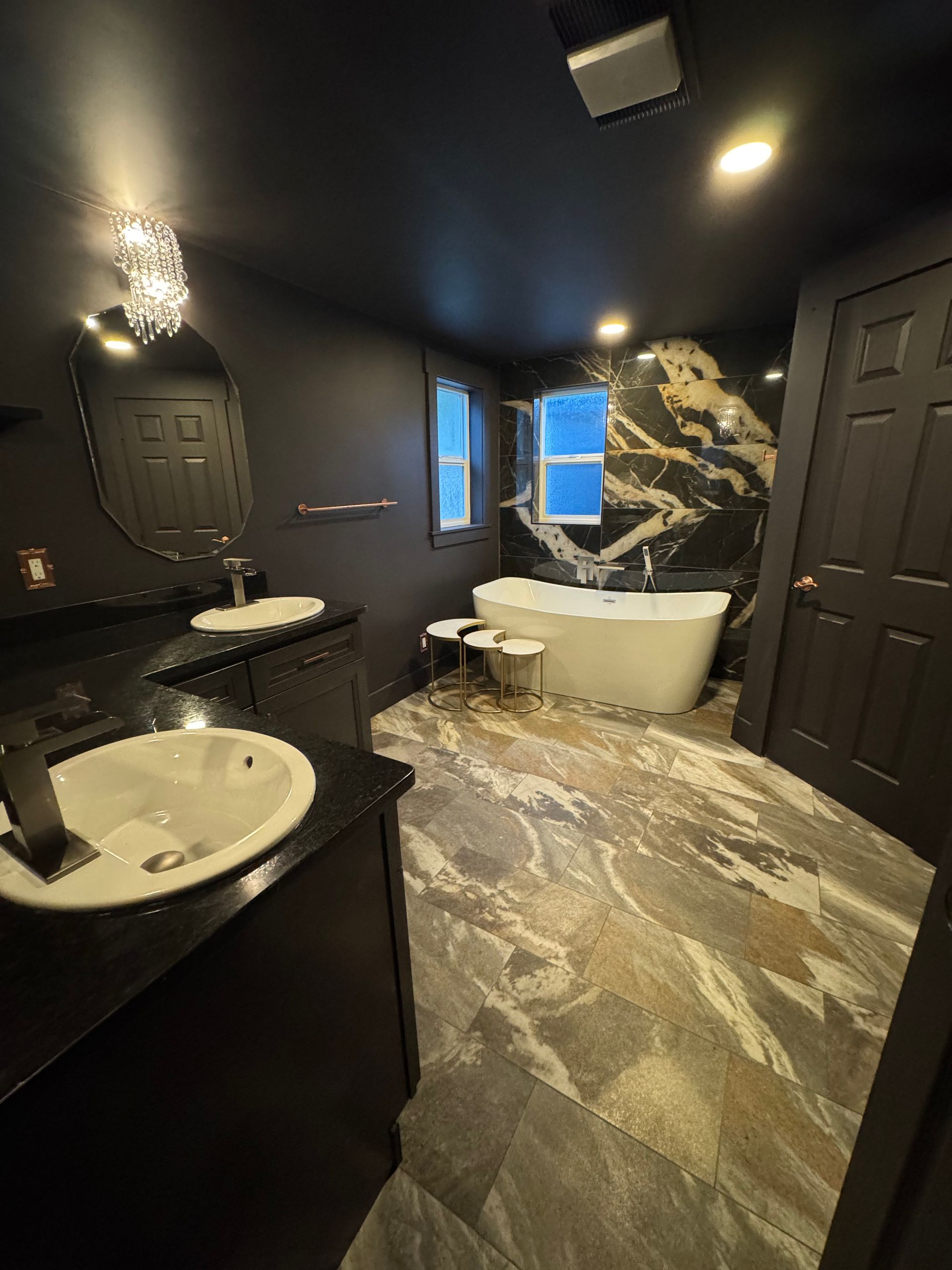 Black and marble bathroom with soaking tub, double vanity, and patterned floor.