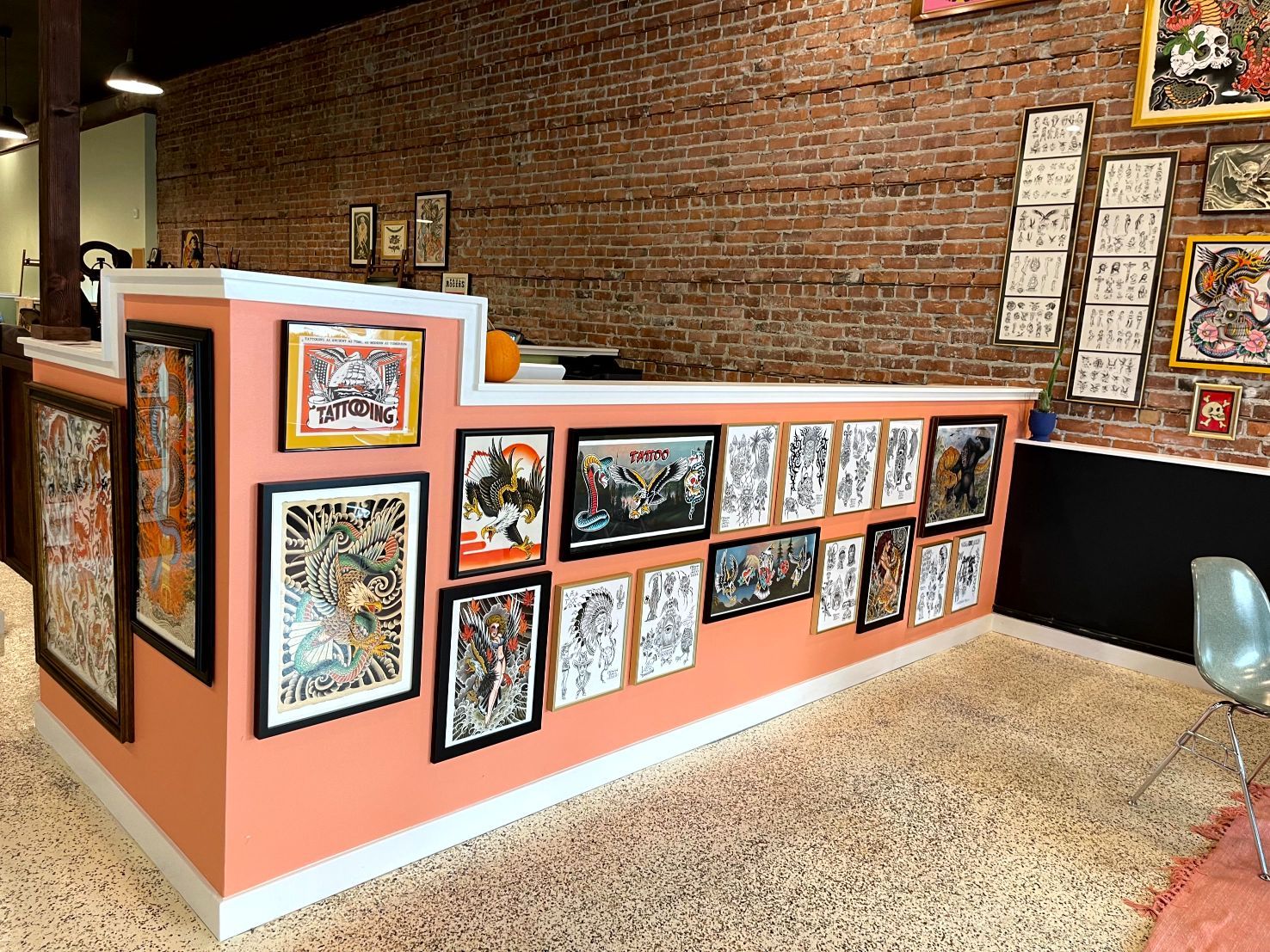 Reception desk in a tattoo parlor with framed art on display.