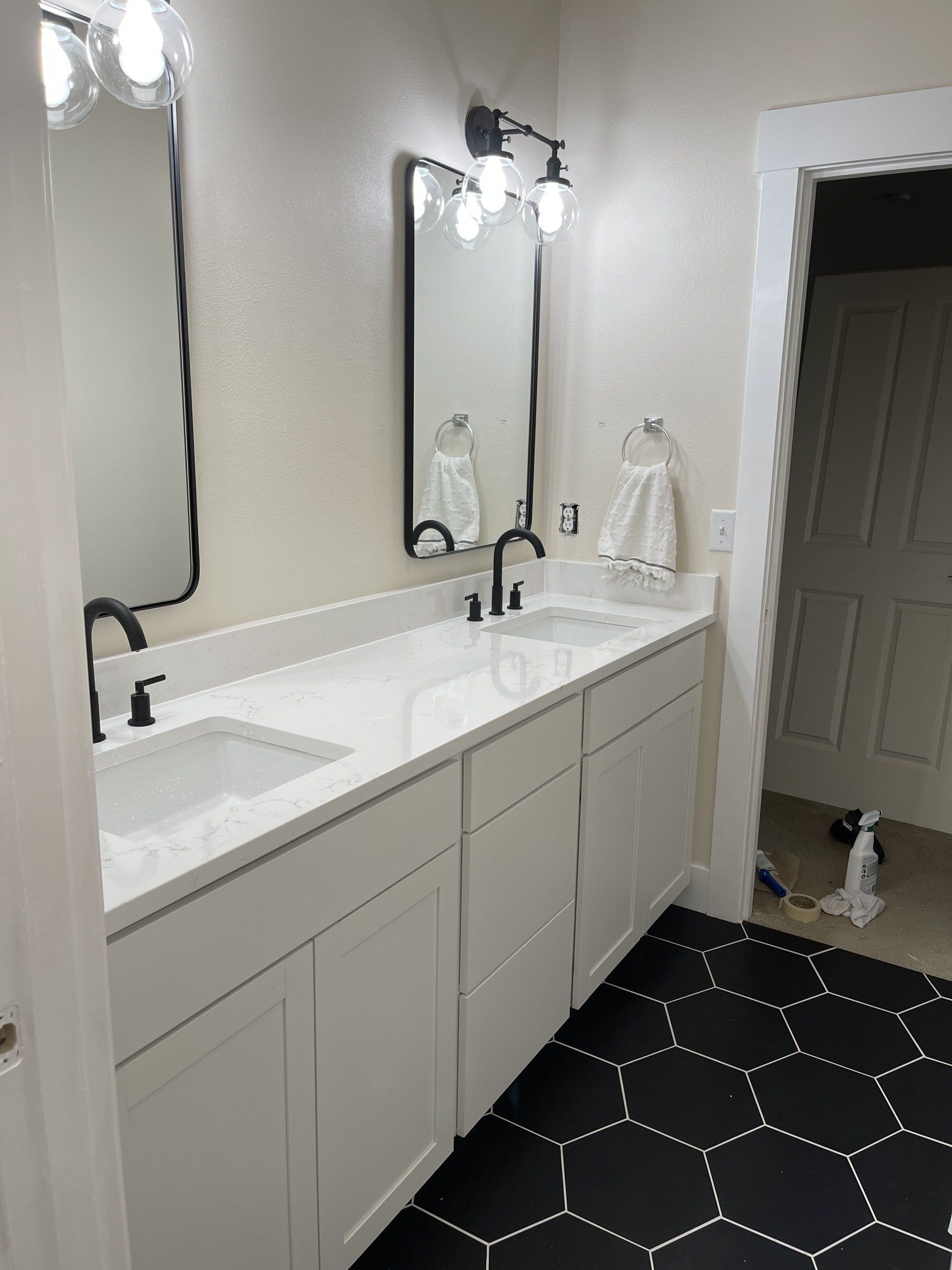 Bathroom with white cabinets, black hexagon tile floor, and black fixtures.