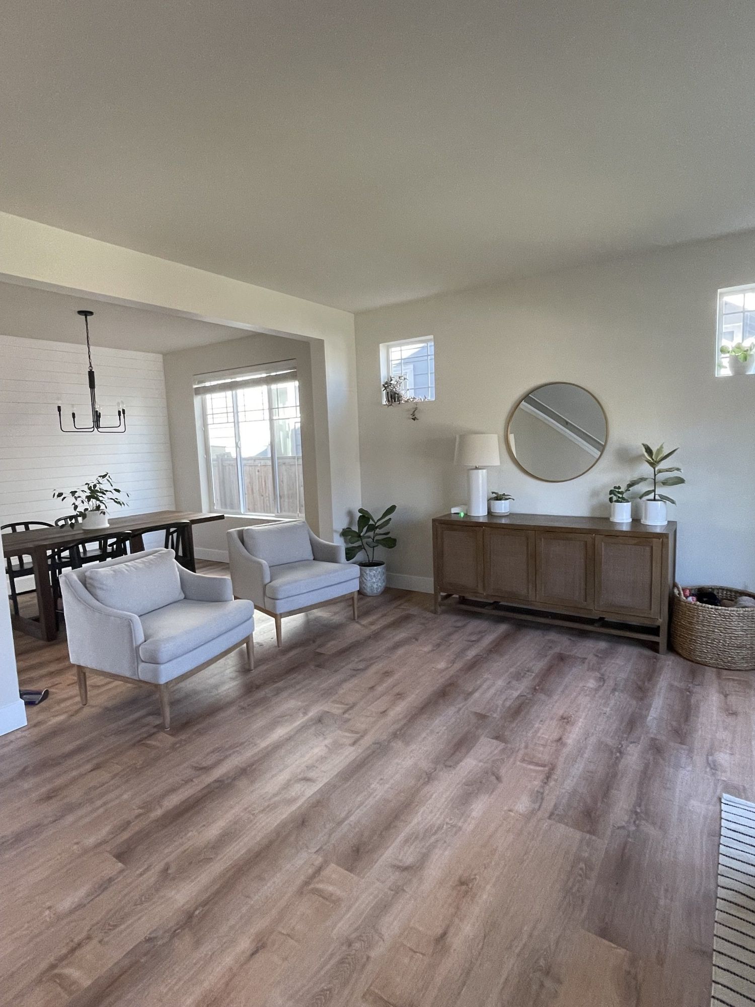 Living room with wood floors, two armchairs, console with mirror, dining table.