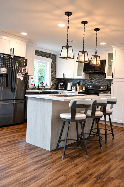 Modern kitchen with black appliances, white island, pendant lights, and bar stools on wood flooring