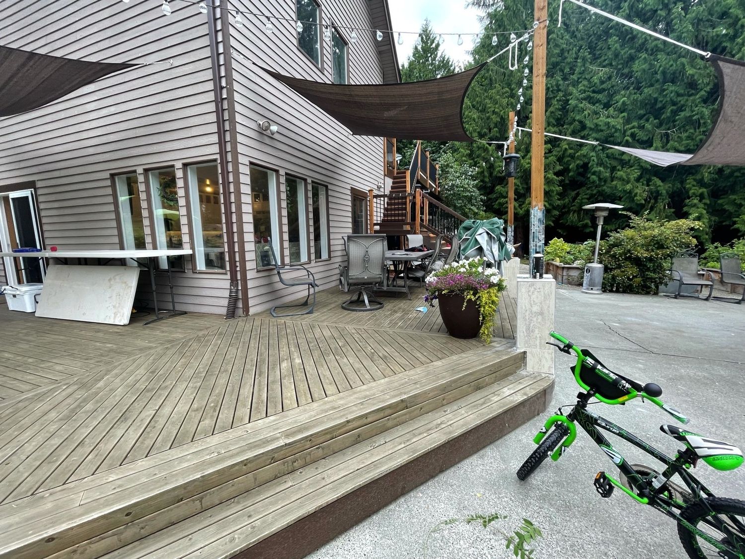 Wooden deck and building exterior with a bicycle in the foreground and a shade structure overhead.