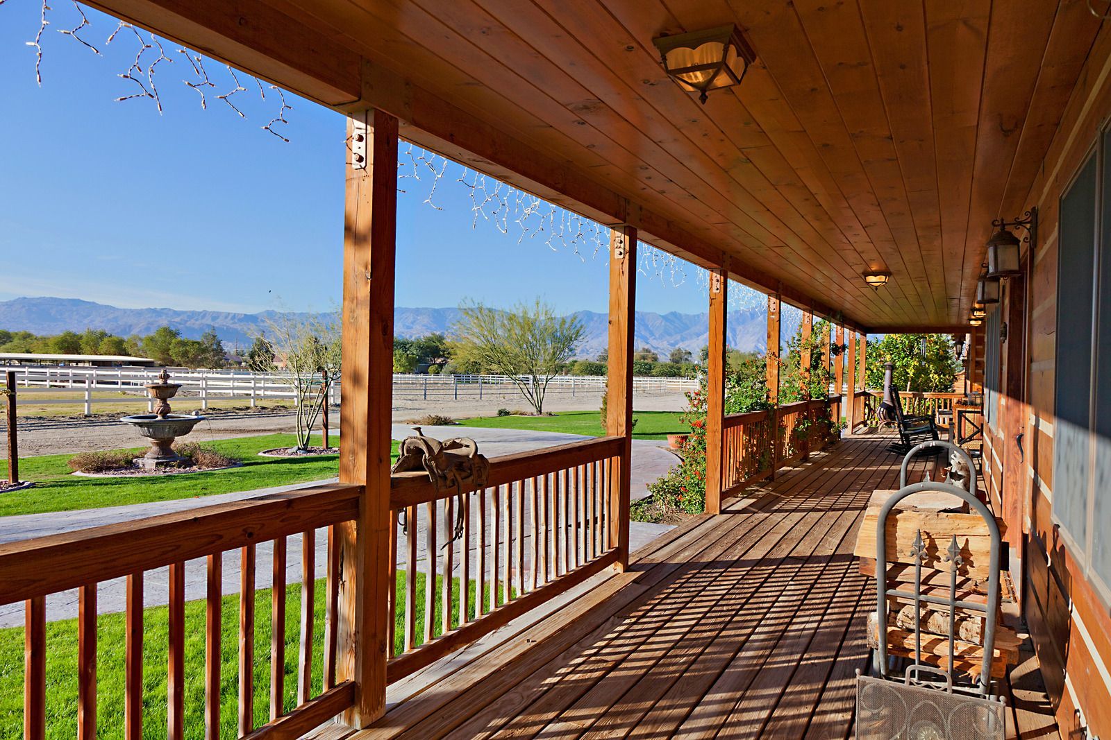 Wooden porch with railing overlooking a bright rural landscape and distant mountains
