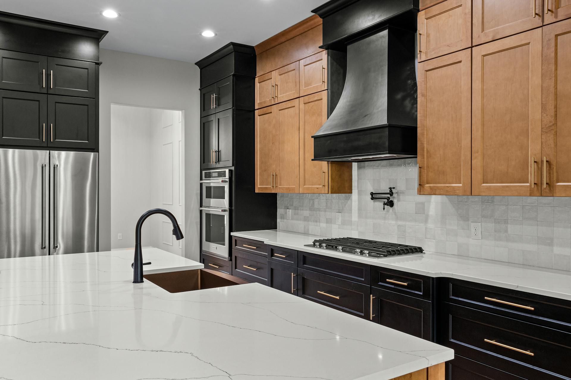 Modern kitchen with white island, black appliances, and wood cabinets