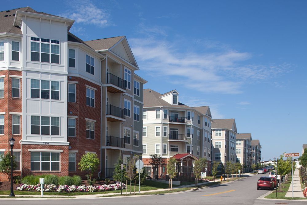 Modern apartment buildings lining a quiet residential street under a blue sky at Verde at Howard Square West Apartments in Elkridge, MD.