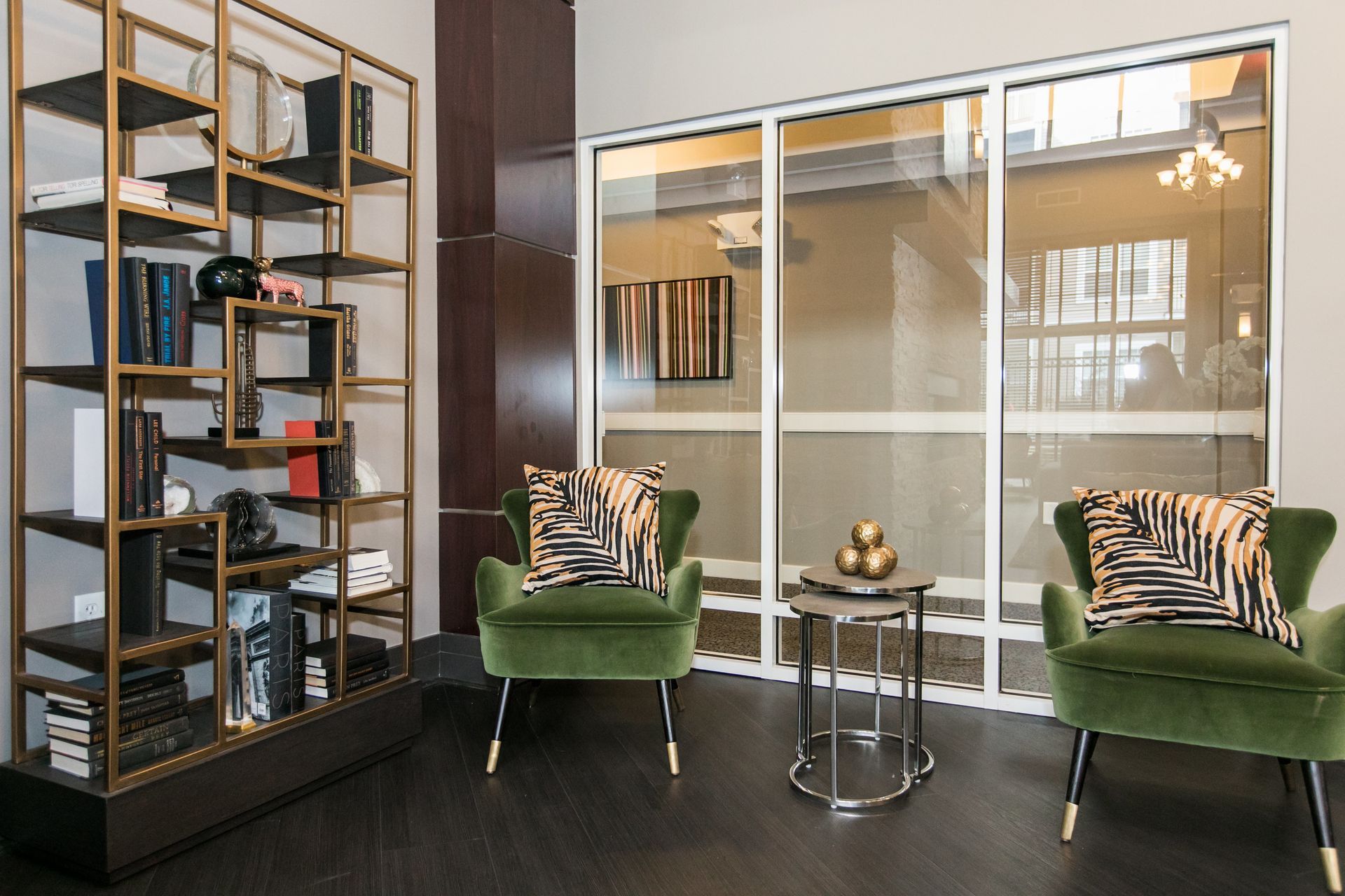 Modern office lounge with green chairs, a glass wall, black shelving, and a small round table at Verde at Howard Square West Apartments in Elkridge, MD.
