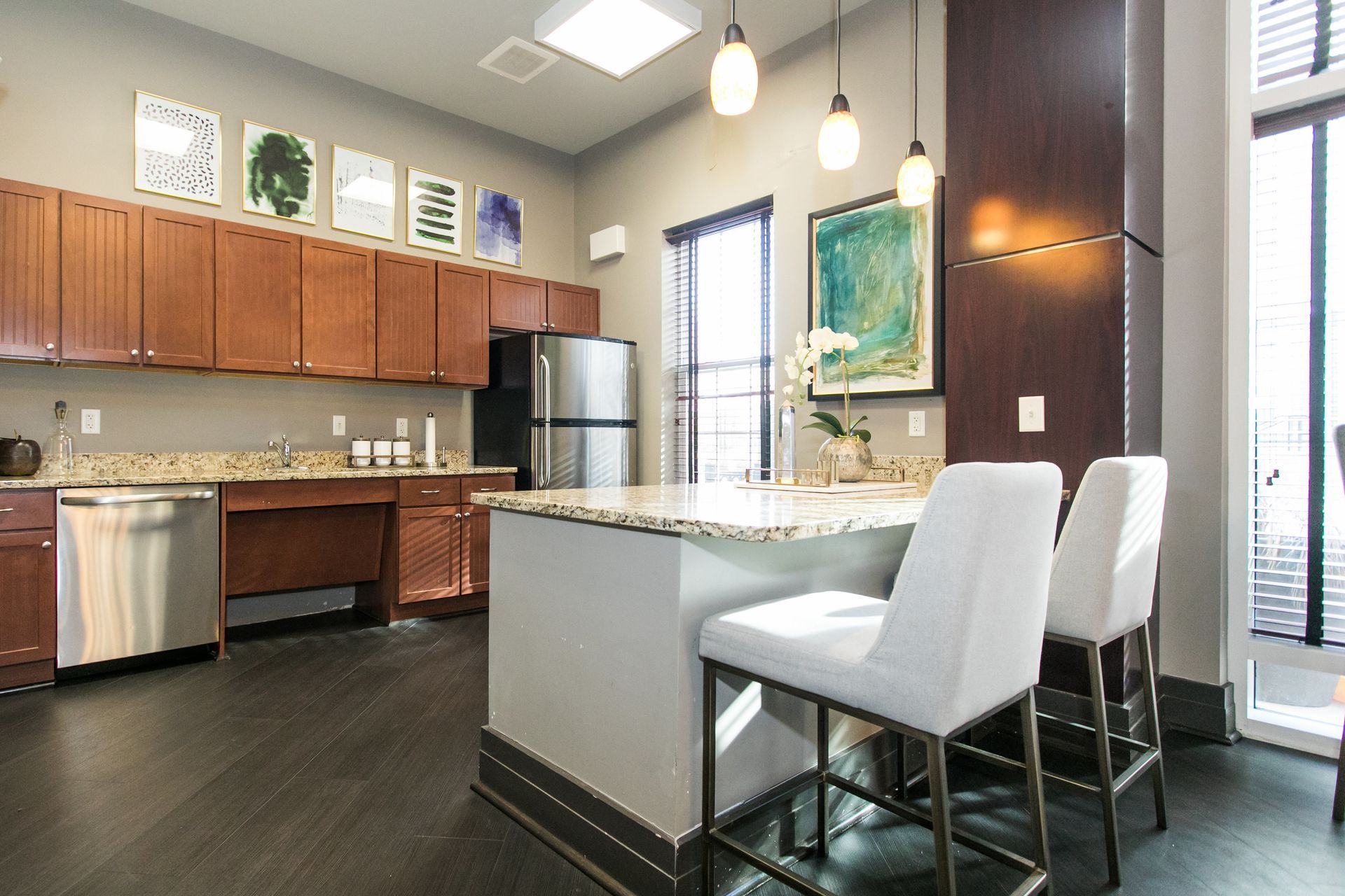 Modern kitchen with island, white bar stools, wood cabinets, and stainless steel appliances at Verde at Howard Square West Apartments in Elkridge, MD.