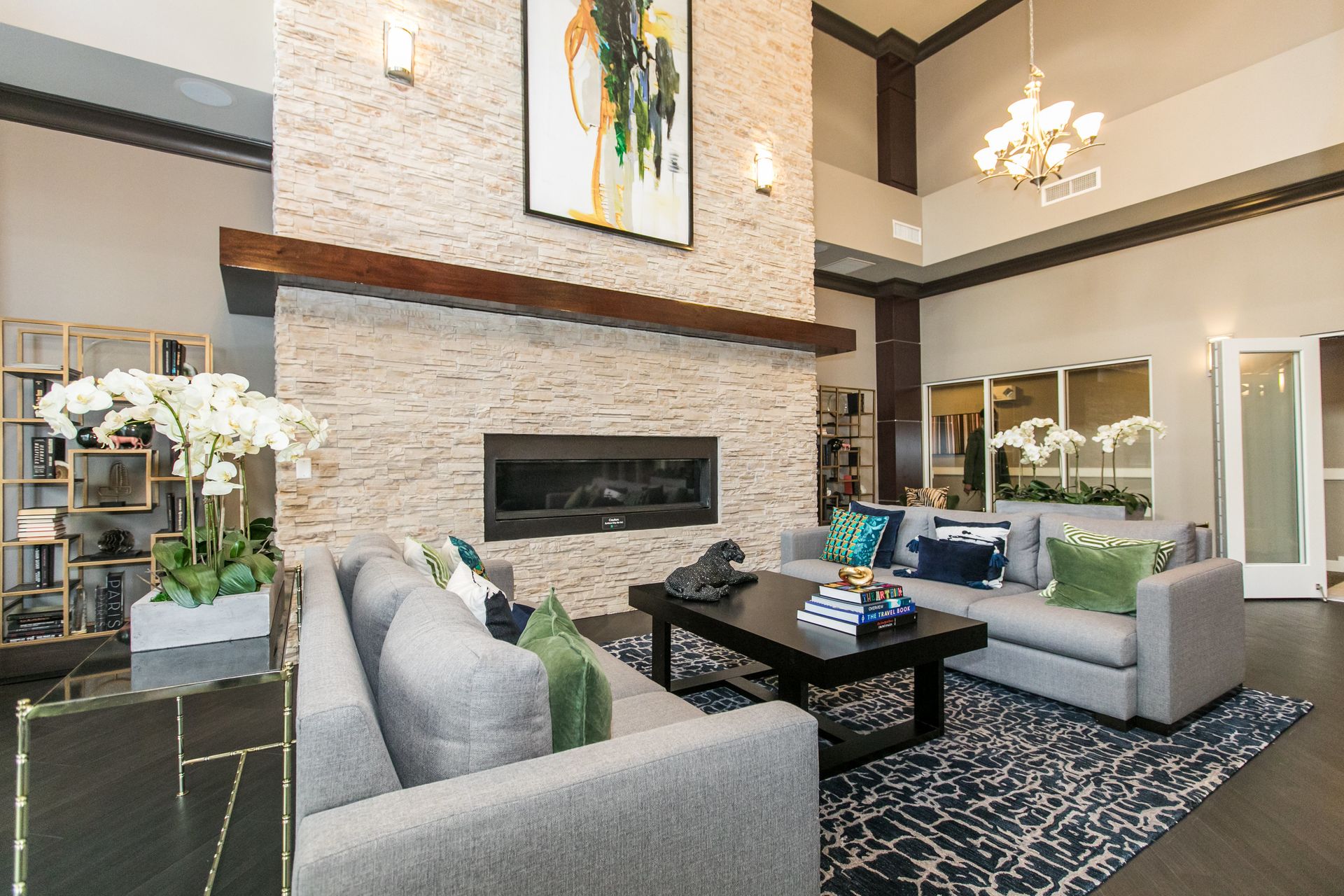 Modern living room with gray sofas, stone fireplace, black coffee table, and high vaulted ceiling at Verde at Howard Square West Apartments in Elkridge, MD.