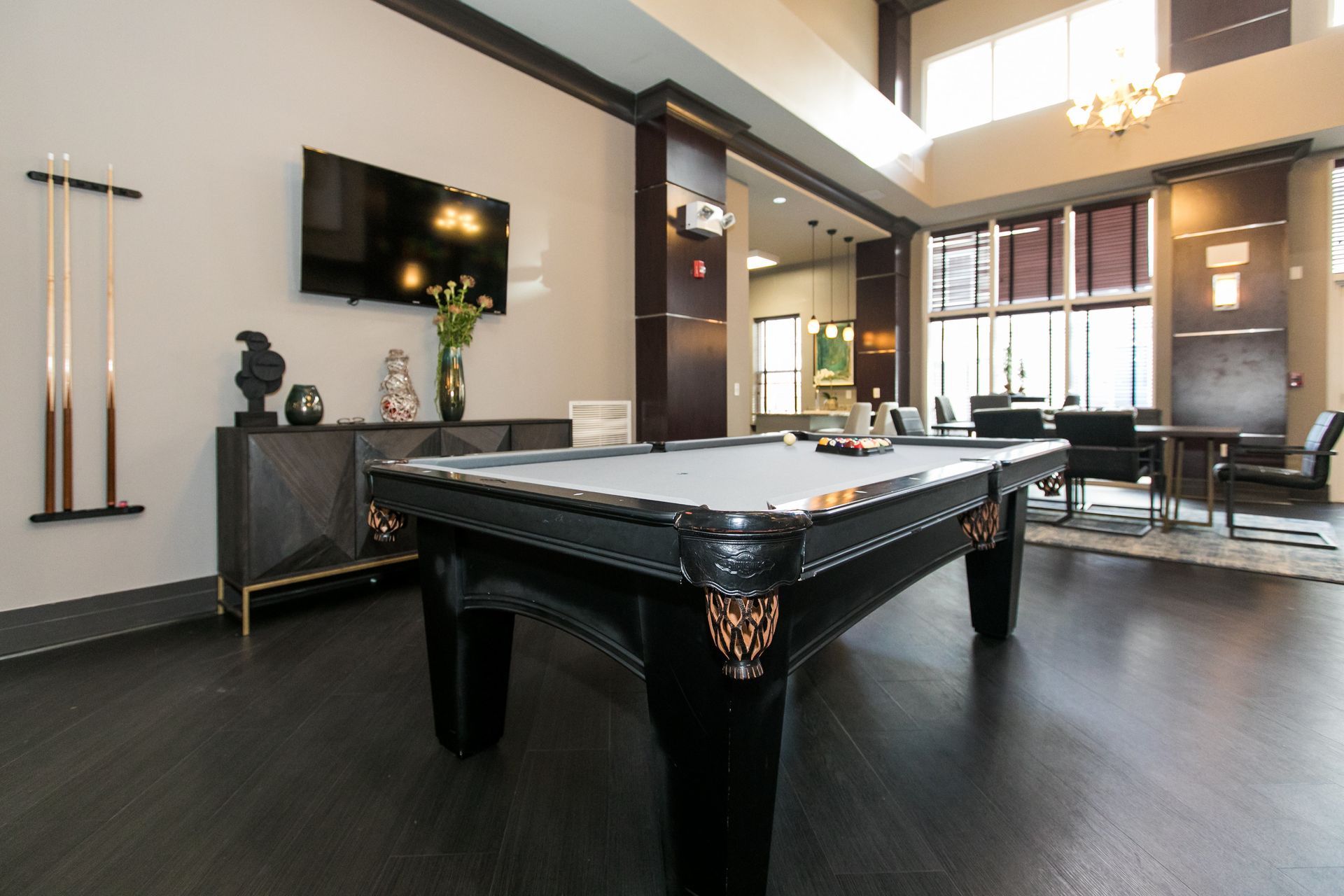 Modern game room with a black pool table, TV, and large windows in a sleek, open interior at Verde at Howard Square West Apartments in Elkridge, MD.